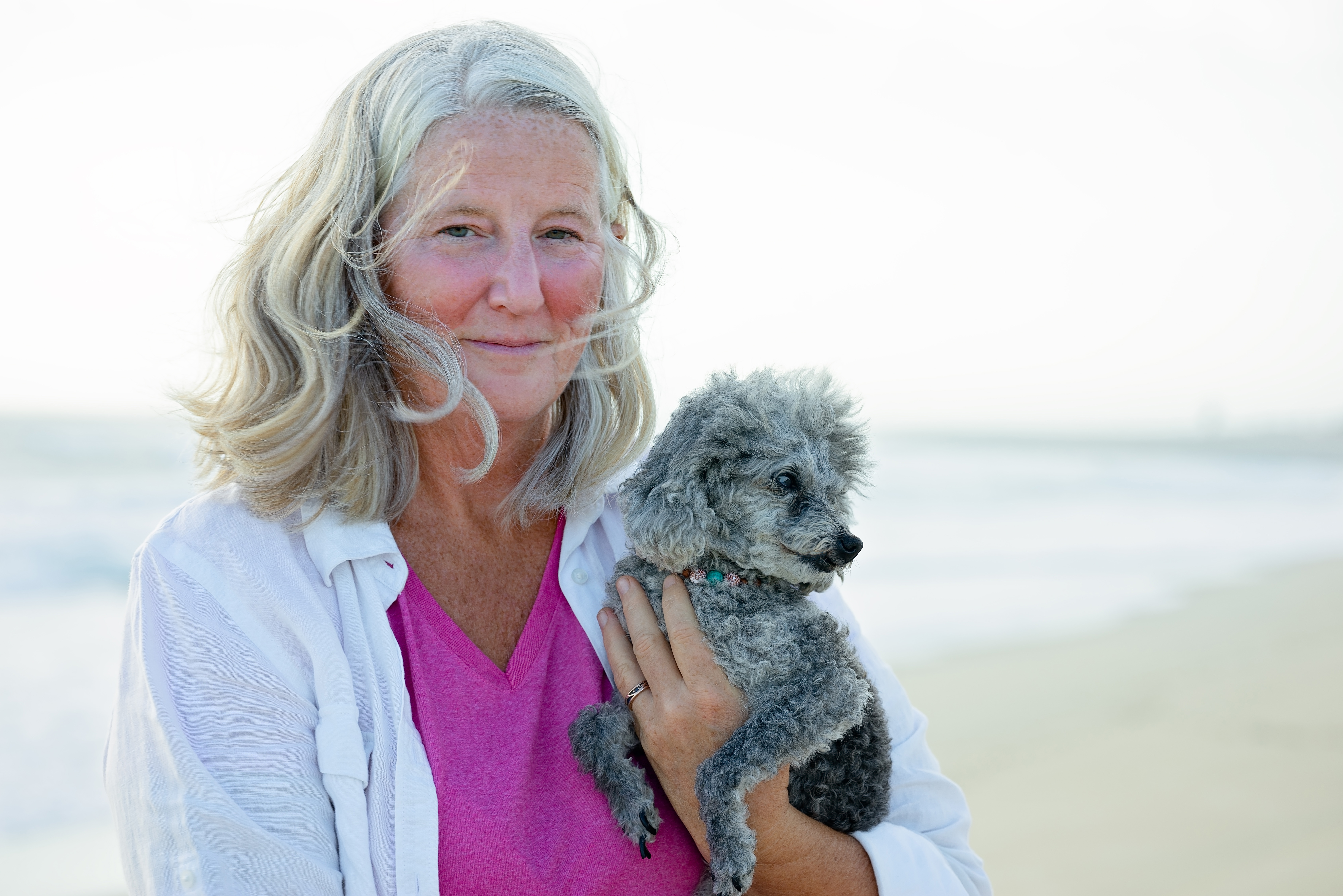 Dr. Ruth Roberts holding her poodle on the beach